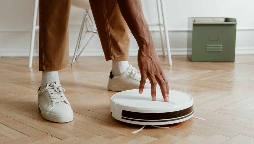 A man turning on a robot vacuum